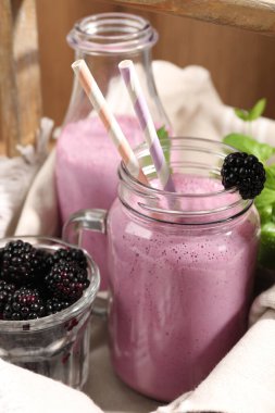 Farklı bardakta lezzetli böğürtlen suyu ve ahşap arka planda taze böğürtlen, yakın plan.