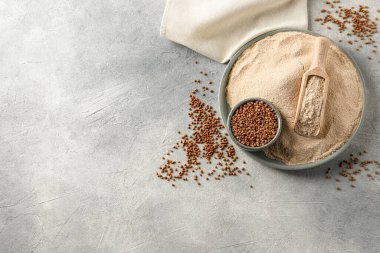 Düz kompozisyon ve gri masa üzerinde bir kase karabuğday unu ve tahıl vardı. Metin için boşluk