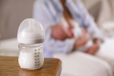 Anne ve küçük bebeği evde, bir şişe süte odaklanıyor. Metin için boşluk