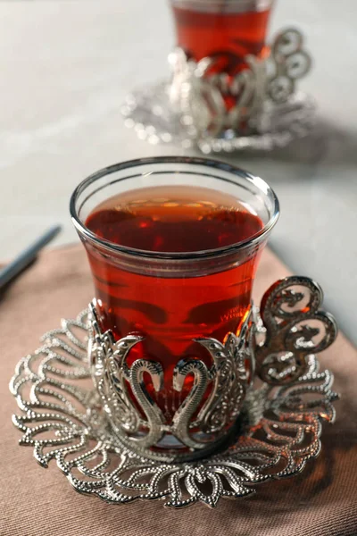 Glasses of traditional Turkish tea in vintage holders on table, closeup