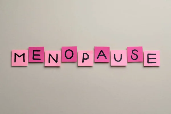 stock image Pink paper notes with word Menopause on beige background, flat lay