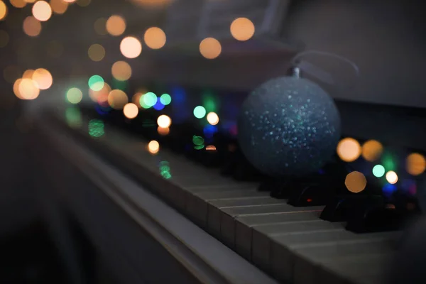 Beautiful bauble and fairy lights on piano keys, space for text. Christmas music