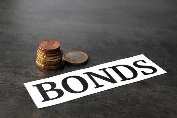 Paper Word Bonds Stacked Coins Grey Table — Stock Photo, Image