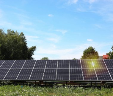 Güneşli bir günde mavi gökyüzünün altındaki ağaçların yakınındaki güneş panelleri. Alternatif enerji kaynağı