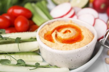 Tabakta lezzetli humus ve taze sebzeler, yakın plan.