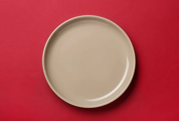 红色背景的空米色陶瓷盘 顶部视图 — 图库照片