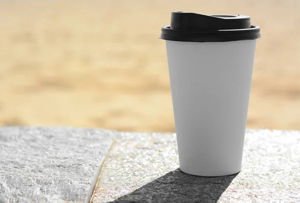 Takeaway coffee cup on stone surface outdoors. Space for text