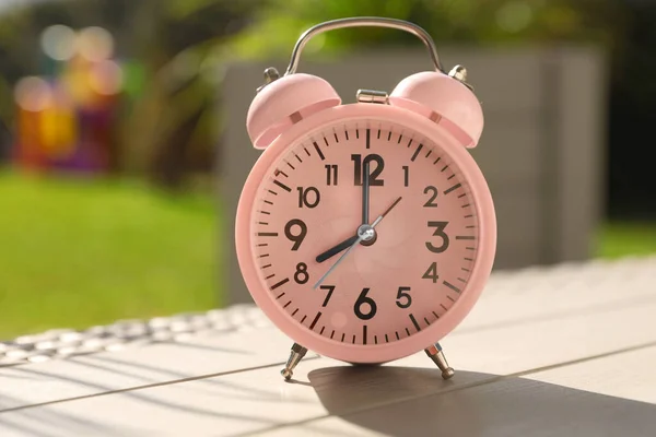 テーブルの上のピンクの目覚まし時計屋外で晴れた朝 — ストック写真