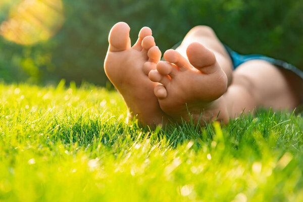 Teenage girl lying barefoot on green grass outdoors, closeup