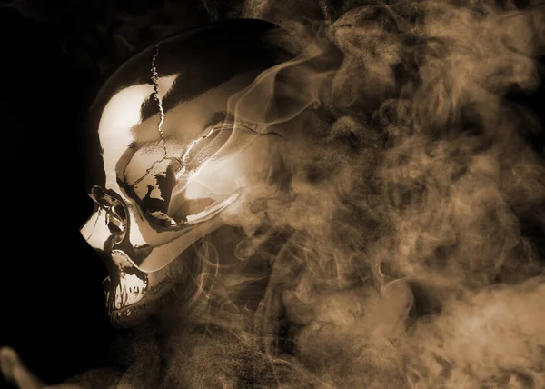 Scary skull emerging from smoke in darkness