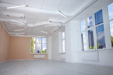 Temiz pencereleri ve aydınlık duvarları olan yeni boş oda