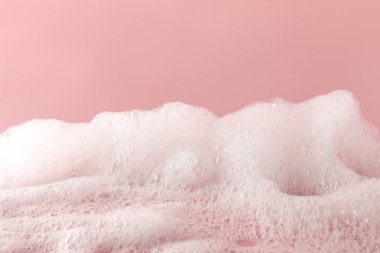 Pembe arka planda tüylü banyo köpüğü, yakın plan. Bakım ürünü