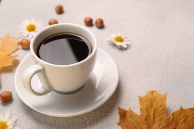 Bir fincan sıcak içecek ve sonbahar yapraklı kompozisyon açık gri desenli masa, yakın çekim