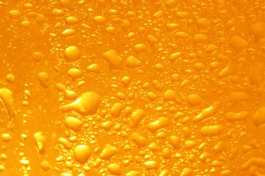 Glass of tasty cold beer with condensation drops as background, closeup