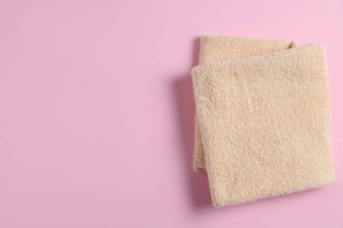 Pembe arka planda yumuşak katlanmış havlu, üst manzara. Metin için boşluk