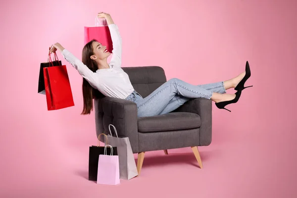 Glückliche Junge Frau Mit Einkaufstaschen Auf Sessel Vor Hellrosa Hintergrund — Stockfoto