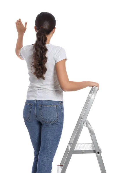 白い背景に金属製のはしごで若い女性 バックビュー — ストック写真