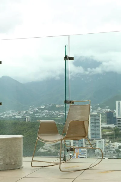 stock image Coffee table and rocking chair against picturesque landscape of city in cafe