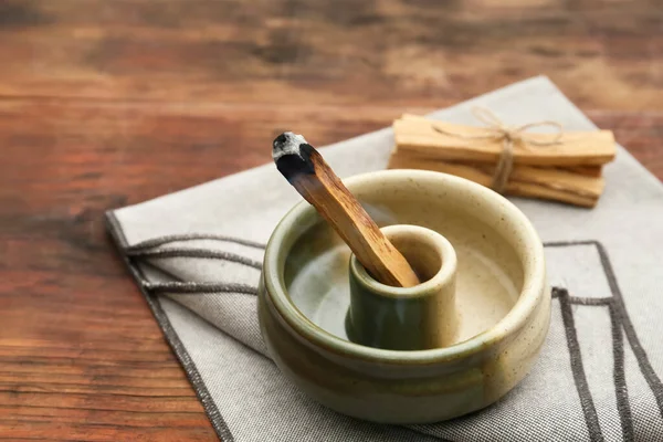 stock image Palo Santo stick smoldering in holder on wooden table