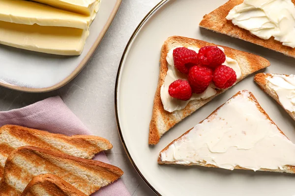 Açık gri masada tereyağı ve ahududu ile lezzetli tostlar.