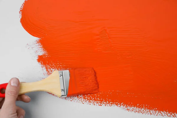 Mann Trägt Orangefarbene Farbe Mit Pinsel Auf Weißem Hintergrund Auf — Stockfoto