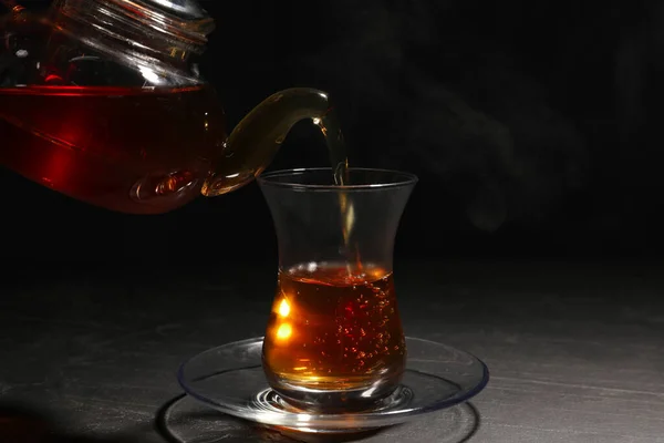 Nalanie Tradycyjnej Tureckiej Herbaty Garnka Szkła Czarnym Stole — Zdjęcie stockowe