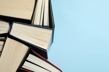 Açık mavi arka plan ve üst görünüm üzerine bir sürü ciltli kitap. Metin için boşluk