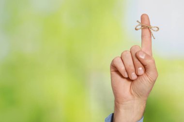 Yeşil bulanık arka planda işaret parmağı ve bağlı yay gösteren bir adam, yakın plan. Metin için boşluk