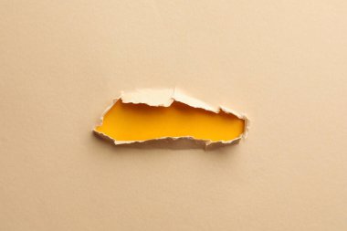 Sarı arkaplanda açık bej kağıtta bir delik
