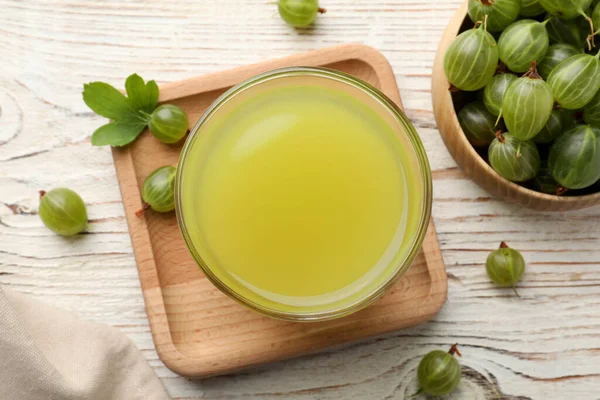 stock image Tasty gooseberry juice and fresh berries on white wooden table, flat lay