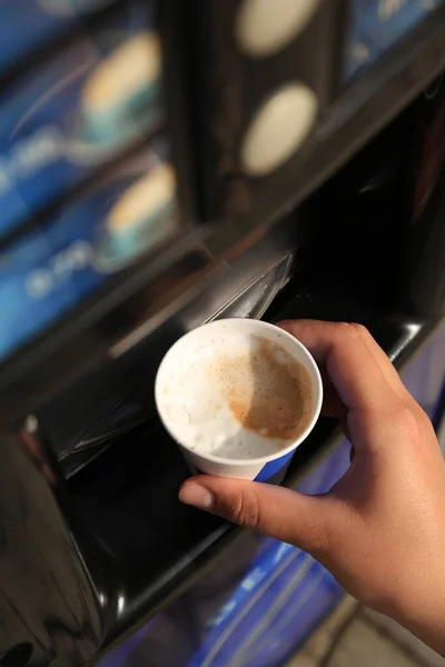 Woman taking paper cup with coffee from vending machine, above view