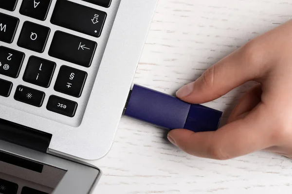 stock image Woman attaching usb flash drive into laptop at white wooden table, top view