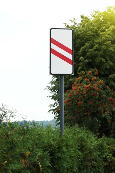 Road sign Countdown Beacon to Railway Crossing near plants outdoors