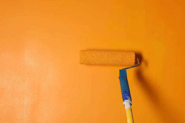 Painting wall with roller and orange dye