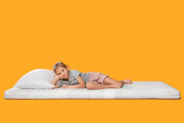 Kleines Mädchen Auf Bequemer Matratze Vor Orangefarbenem Hintergrund Platz Für — Stockfoto