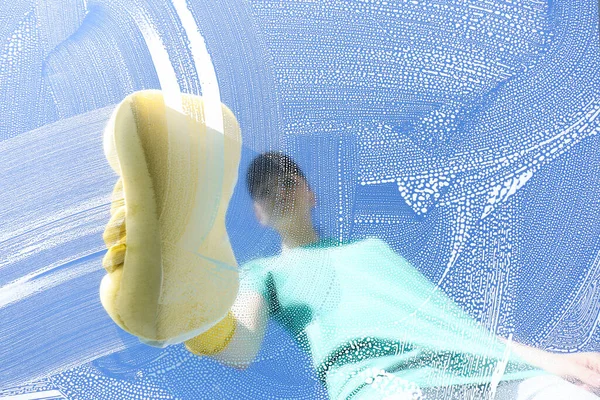 Woman cleaning glass with sponge on sunny day