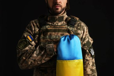 Soldier in military uniform with Ukrainian flag on black background, closeup clipart