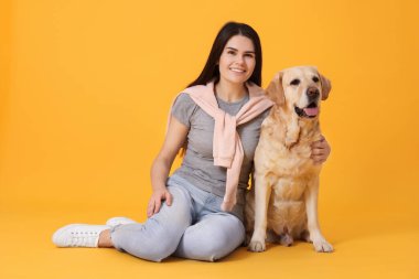 Turuncu arka planda şirin Labrador Retriever 'ı olan mutlu kadın portresi
