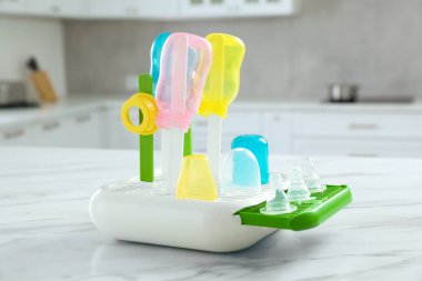 Bebek şişeleri ve meme uçlarıyla kurutucu. Sterilizasyondan sonra mutfaktaki beyaz mermer masada.