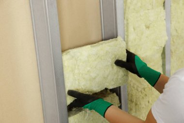 İşçi, duvara termal yalıtım malzemesi yerleştiriyor.