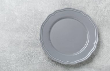 Açık gri masada boş seramik tabak, üst manzara. Metin için boşluk