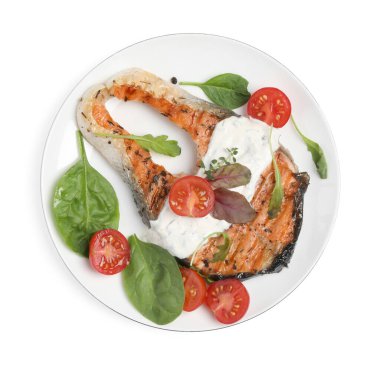 Beyaz arka planda fesleğenli ve domatesli lezzetli somon bifteği.