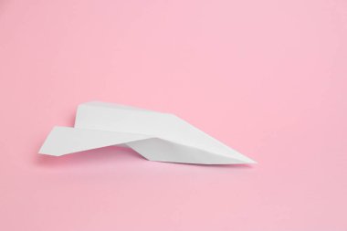 Pembe zemin üzerinde beyaz kağıt uçak, metin için boşluk