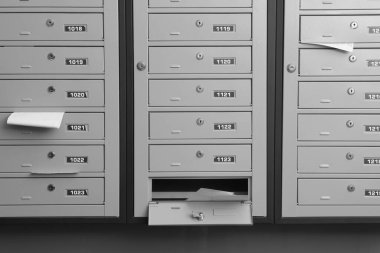 İçinde makbuzlar ve zarflar olan gri metal posta kutuları.