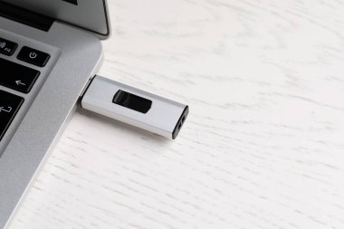 Modern USB flaş bellek, beyaz ahşap masadaki dizüstü bilgisayara bağlı. Metin için boşluk