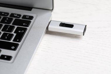 Modern USB flaş bellek beyaz tahta masadaki dizüstü bilgisayara bağlı, yakın plan.