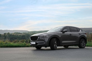 Siyah modern araba asfalt yolda park edilmiş.