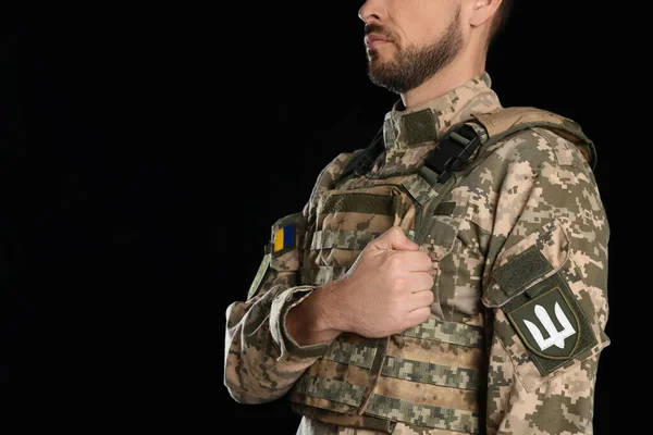 黒を背景にした軍の制服にウクライナのトライデントを持つ兵士 テキストのスペース — ストック写真