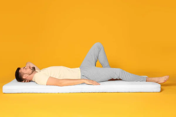 Hombre Durmiendo Sobre Colchón Suave Sobre Fondo Naranja —  Fotos de Stock