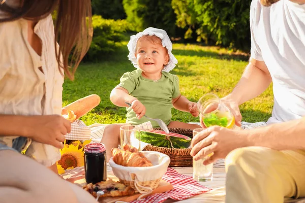 かわいい子供と彼女の両親が庭で晴れた日にピクニックをして — ストック写真